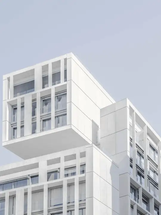 Edificio blanco de ventanas pequeñas bajo un cielo azul pálido