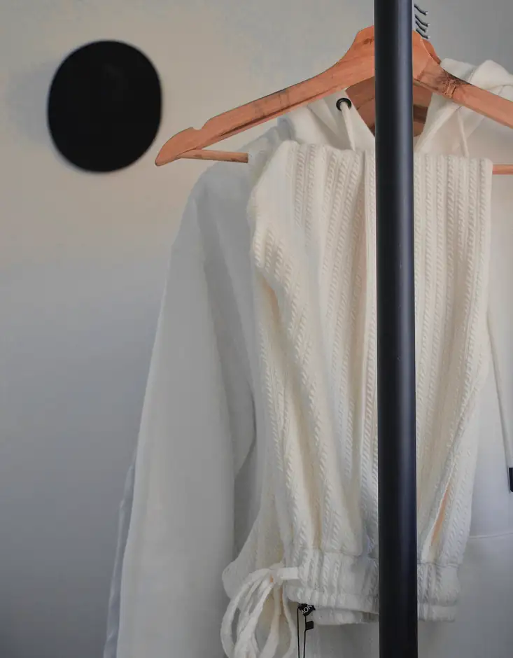 Blusa blanca de mangas atadas colgada de un perchero de madera