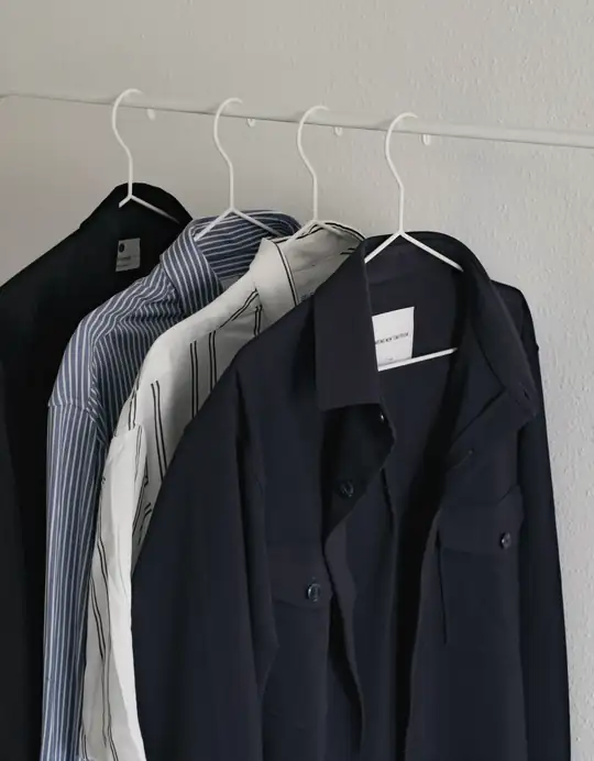 Camisas azules y blancas colgadas en fila de un perchero blanco