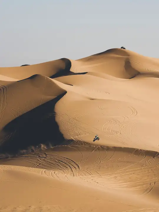 Dunas con un camino de huellas y una figura diminuta
