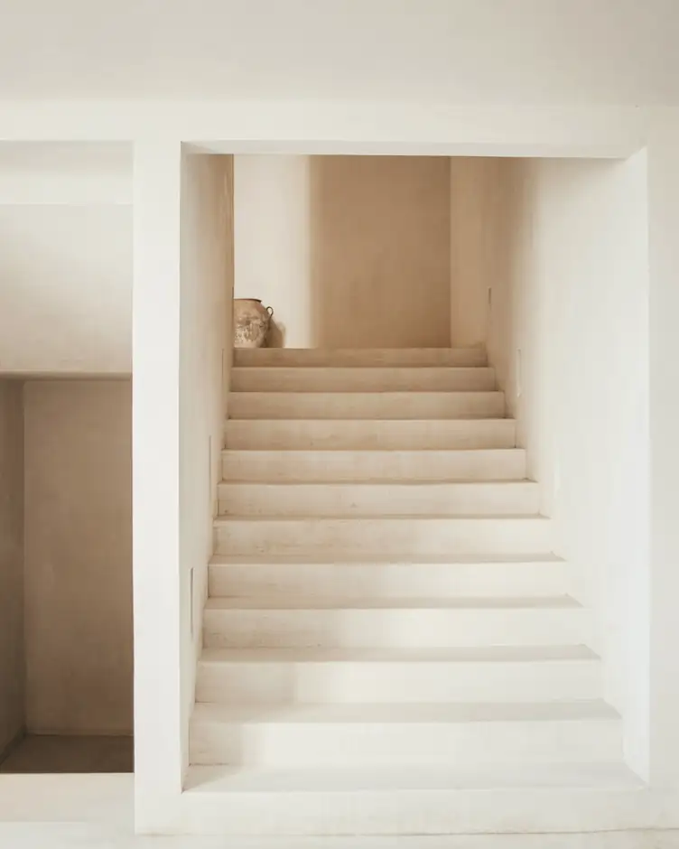 Escalera clara de hormigón entre muros blancos