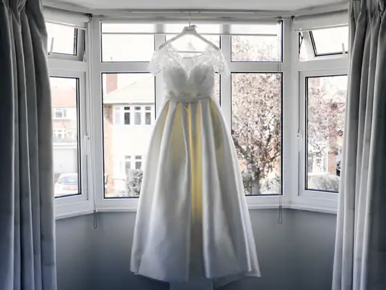 Vestido blanco colgado en el mirador de una casa, entre cortinas
