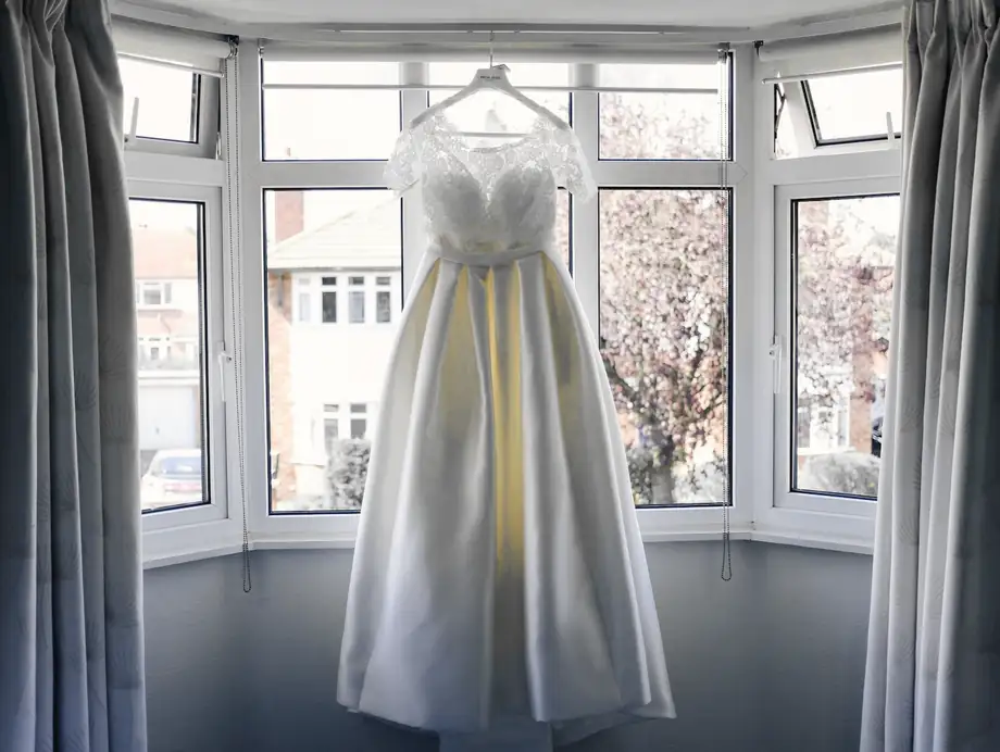 Vestido blanco colgado en el mirador de una casa, entre cortinas