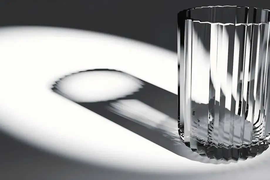 Vaso de vidrio con su sombra larga sobre fondo blanco