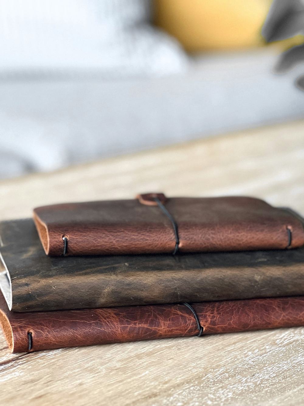 Tres cuadernos de cuero apilados sobre una mesa de madera