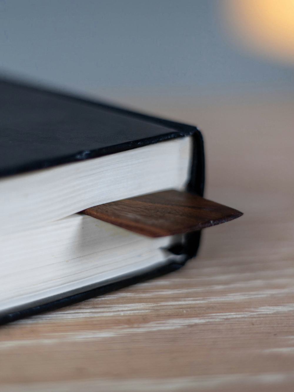 Cuaderno de tapa negra con una lámina de madera como marcapáginas