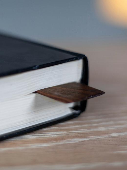 Cuaderno de tapa negra con una lámina de madera como marcapáginas