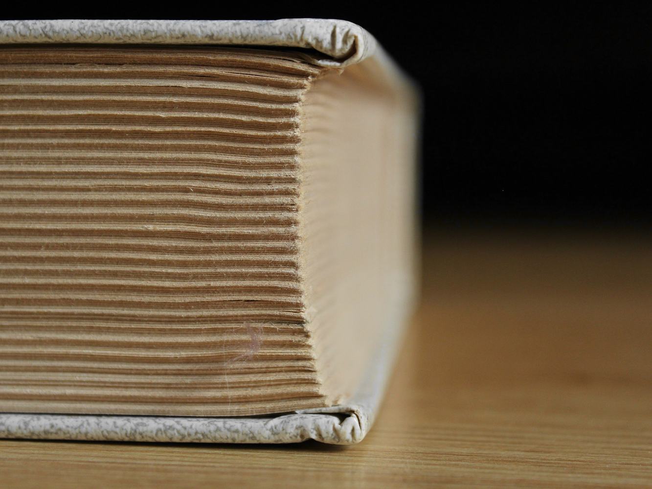 Canto de un libro grueso sobre una mesa de madera