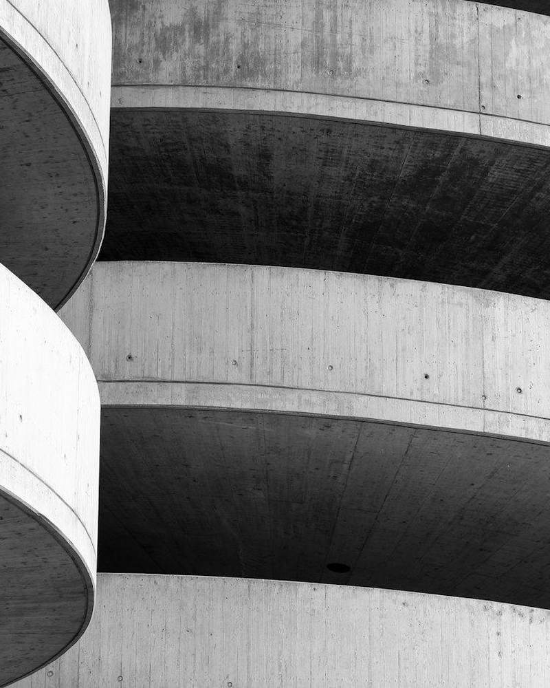 Muro de hormigón curvo con franjas de luz y sombra, en blanco y negro