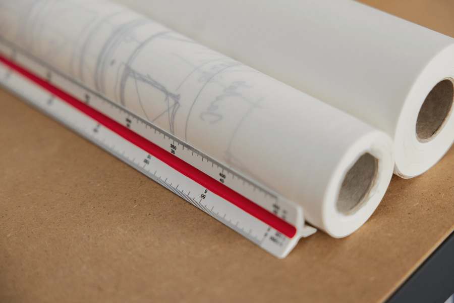 Rollos de planos junto a una escala triangular sobre un tablero