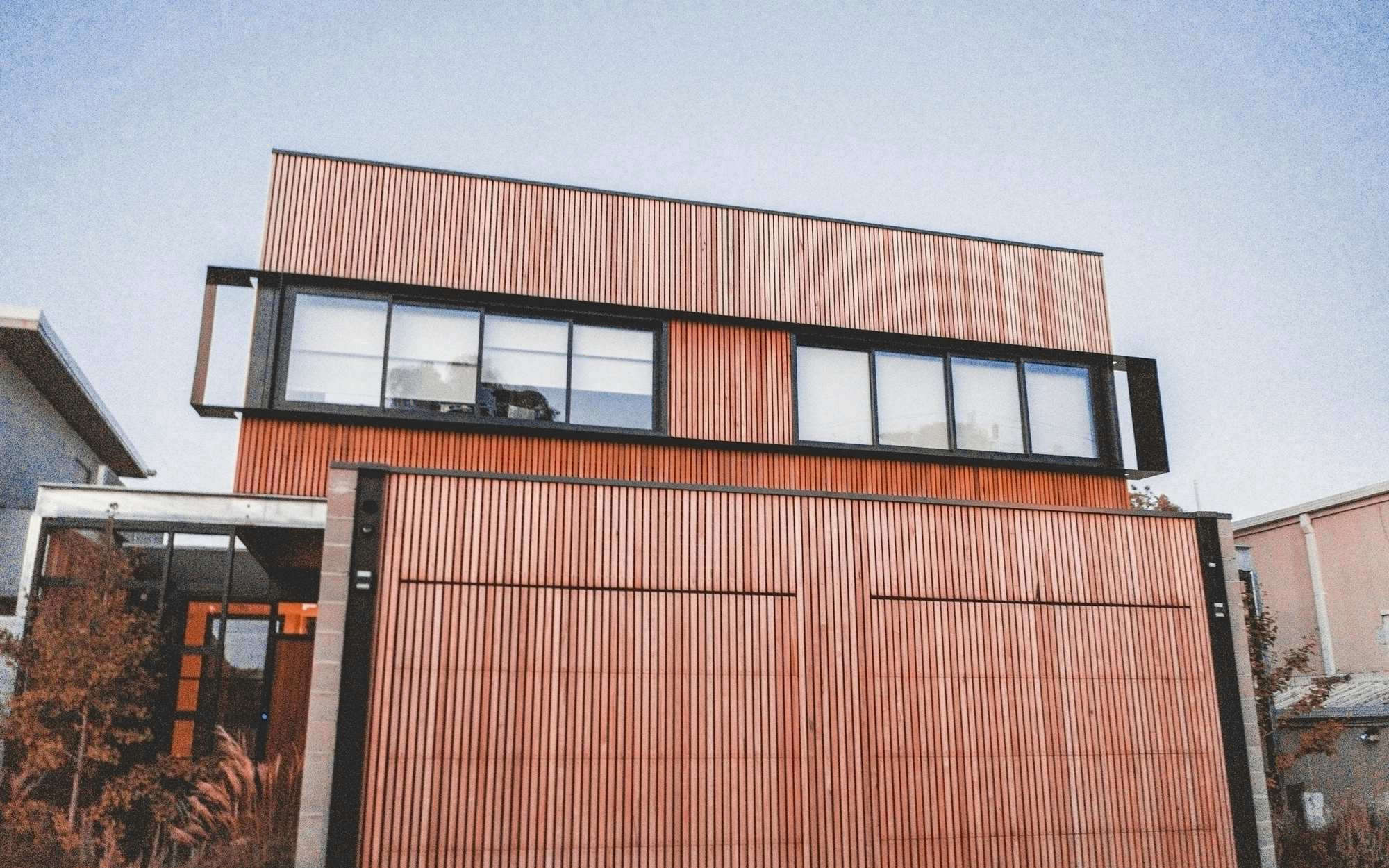 Casa de fachada de listones de madera cobriza en una calle, bajo un cielo claro