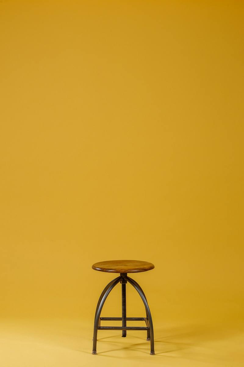 Taburete de madera y acero sobre un fondo amarillo