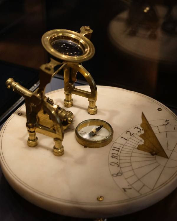 Instrumento de latón con un reloj de sol sobre una base de mármol