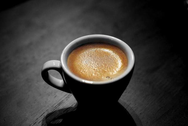 Taza de café con espuma sobre fondo negro