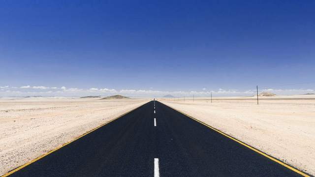 Carretera vacía que cruza un desierto bajo un cielo azul