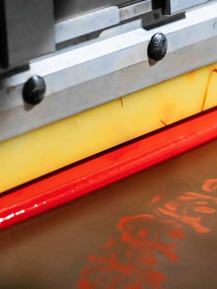 Rasqueta de serigrafía con tinta roja y amarilla