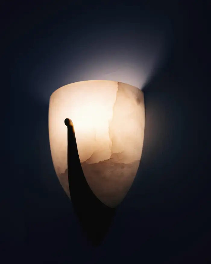 Aplique de alabastro encendido sobre una pared azul oscuro