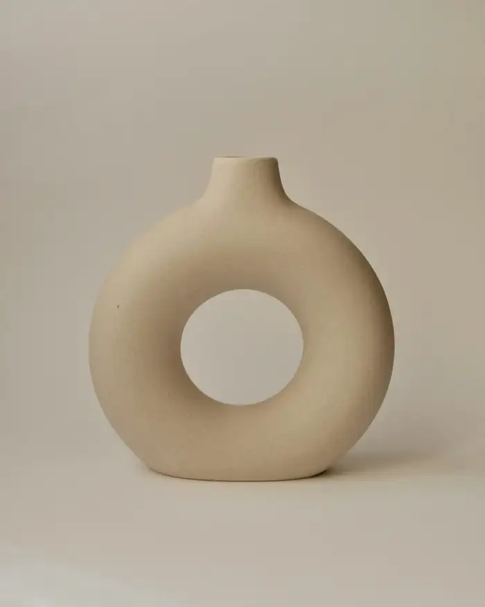 Jarrón de gres en forma de anillo, color crudo, sobre un fondo liso