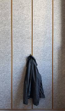 Un abrigo gris colgado de un panel de fieltro con molduras de madera