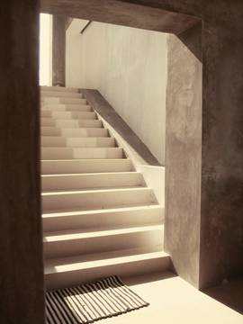 Una escalera interior con una franja de luz en el suelo