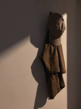 Una gorra y una chaqueta colgadas de una pared, con una sombra larga