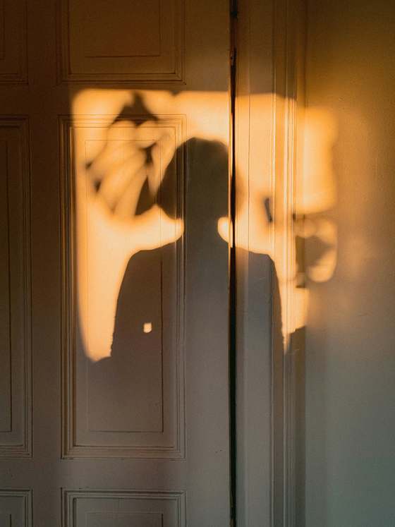 Una silueta dorada de una persona contra una pared iluminada