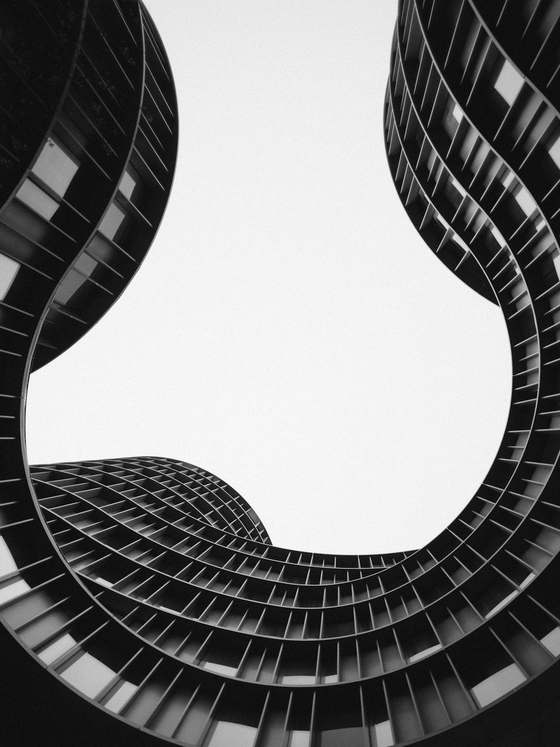 Fachada curva de un edificio de viviendas vista desde abajo, en blanco y negro
