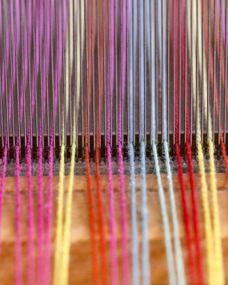 Hilos de colores tensados en un telar, vistos de cerca
