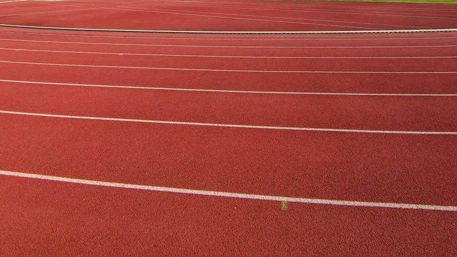 Pista de atletismo roja con las líneas blancas de las calles