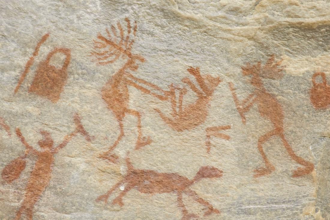 Pinturas rupestres de figuras rojizas, personas y animales, sobre una pared de roca clara