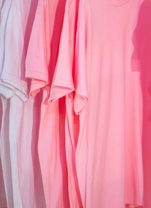 Camisetas rosadas y blancas colgadas en fila