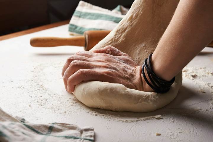Manos amasando sobre una mesa enharinada