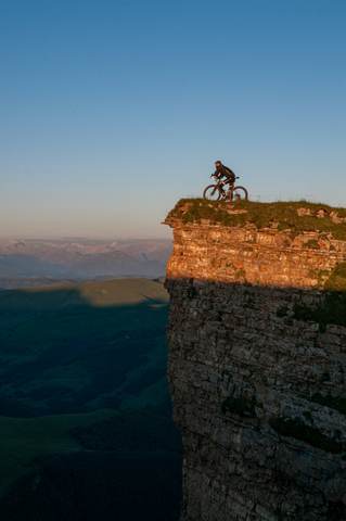 Ciclista en la cima de un acantilado al atardecer