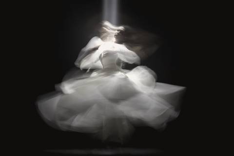Giro de una falda blanca captado en movimiento sobre fondo oscuro