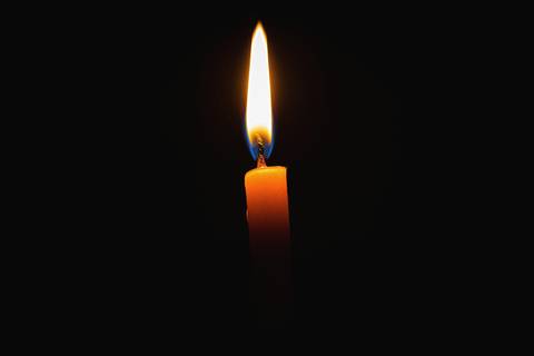 Vela naranja encendida sobre fondo negro