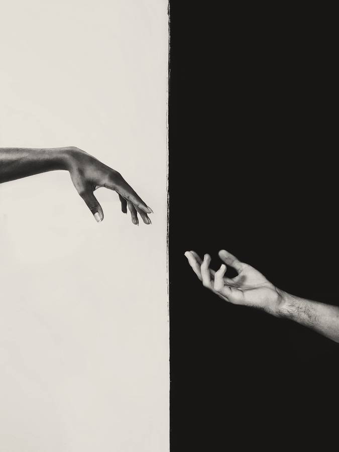 Dos manos que se acercan a través de un fondo dividido en blanco y negro
