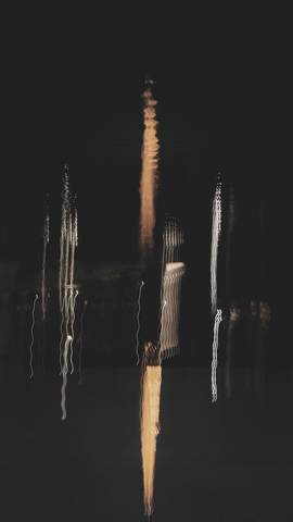 Reflejos alargados de luz sobre agua oscura