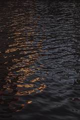 Reflejos naranjas sobre agua oscura