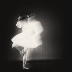 Figura en movimiento con un vestido blanco desenfocado sobre fondo negro