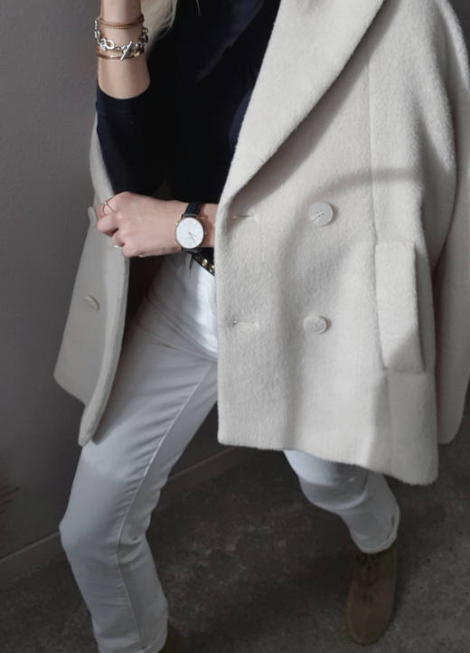 Abrigo cruzado color crudo sobre un suéter oscuro y un pantalón claro