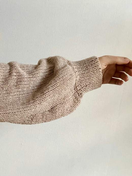 Manga de un suéter de punto beige con la mano extendida
