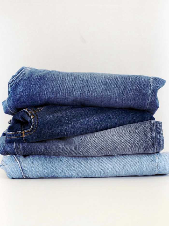 Pila de jeans doblados en distintos tonos de azul sobre fondo blanco