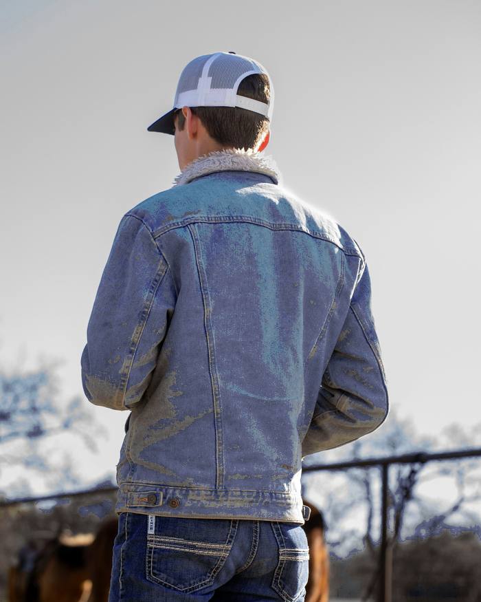 Persona de espaldas con chaqueta de mezclilla y gorra