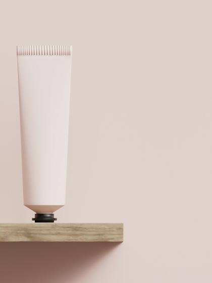 Tubo rosado en pie sobre una repisa de madera, con fondo rosa pálido