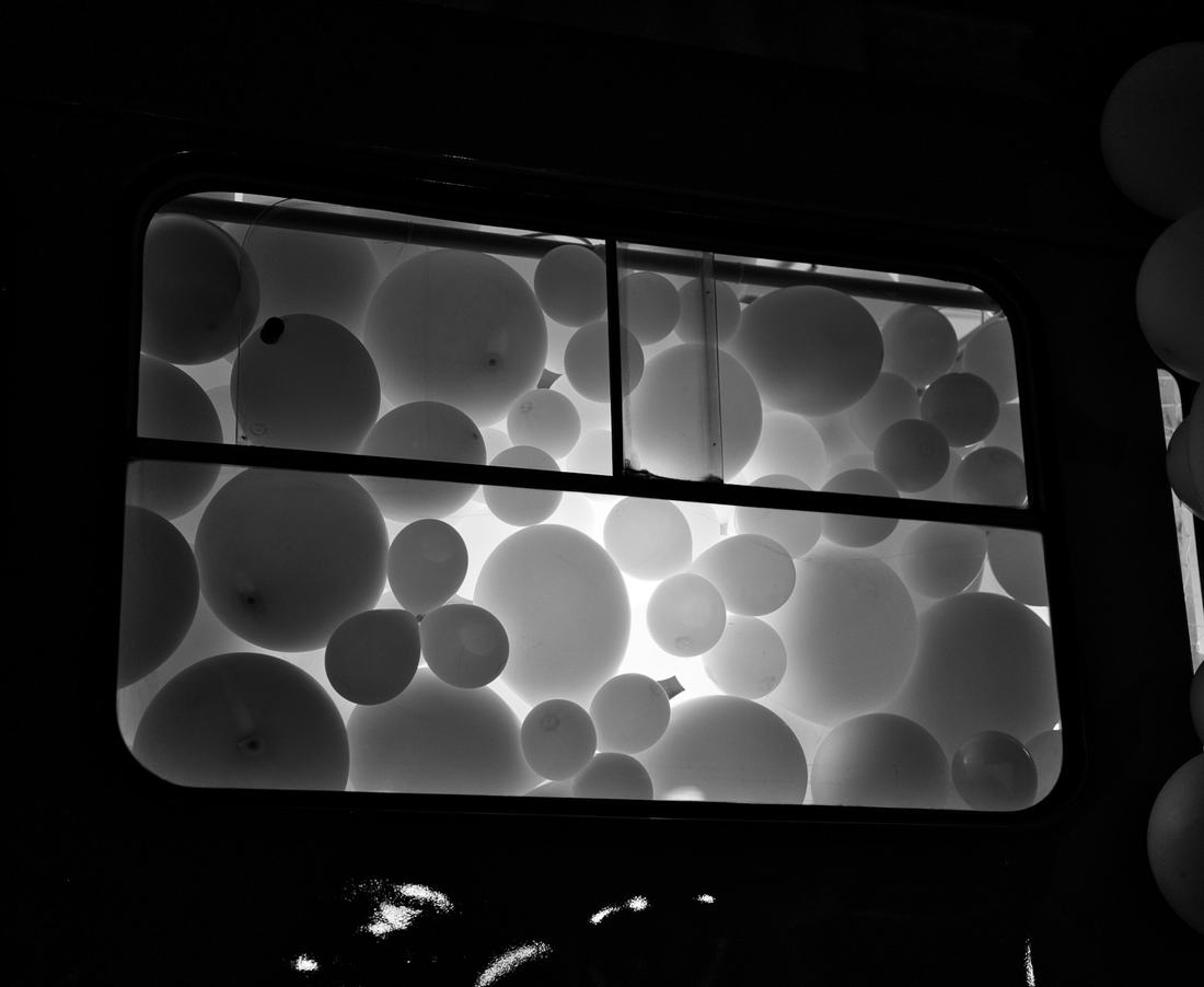 Globos blancos dentro de una ventana, en blanco y negro