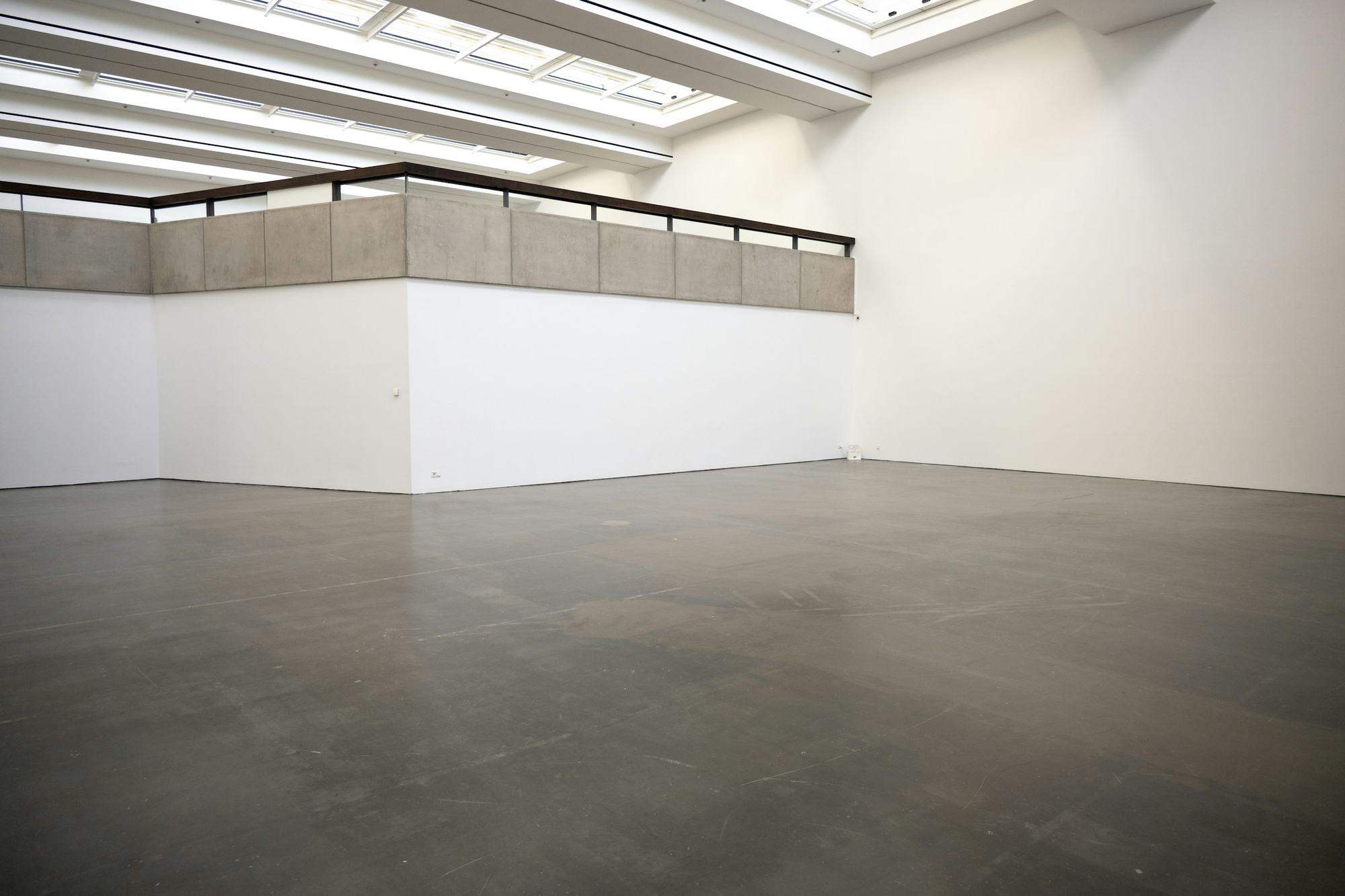 Sala amplia de paredes blancas y piso de cemento
