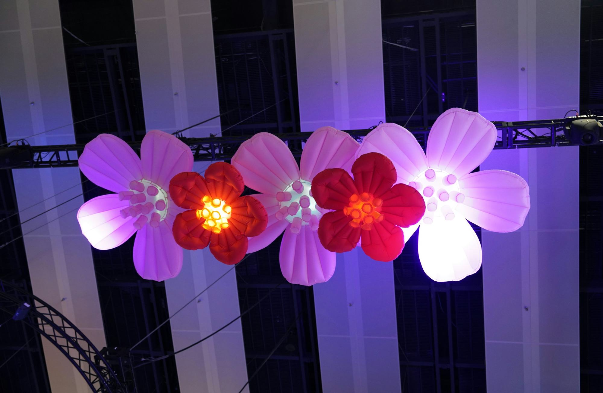Flores inflables blancas y rojas, iluminadas, colgadas de un techo