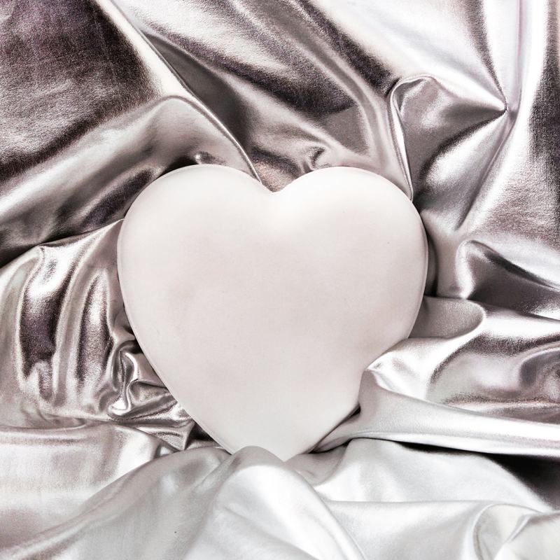 Corazón blanco sobre una lámina plateada arrugada
