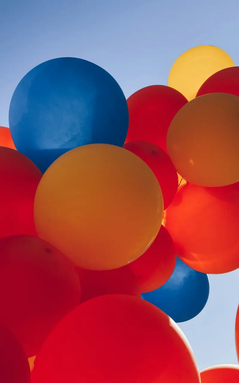 Globos grandes rojos, azules y naranjas contra el cielo