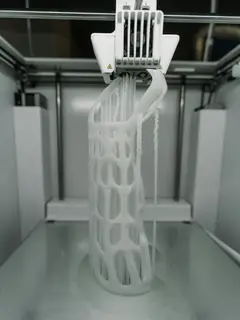 Pieza blanca calada saliendo de una impresora 3D